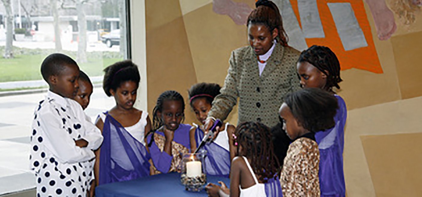 Rwandan women and children light a memorial candle