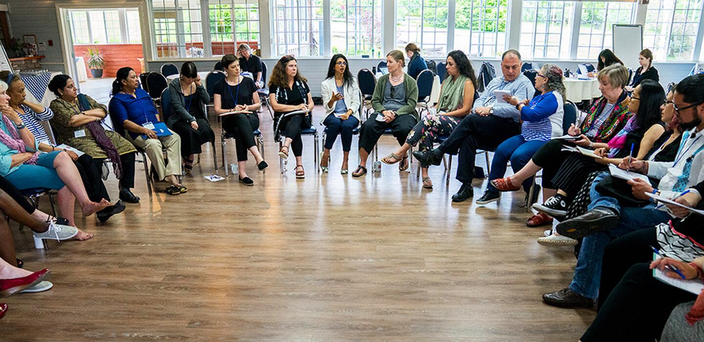 A large group of participants in a semi circle discussing 